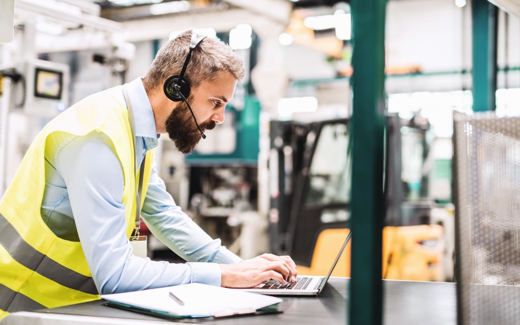 Industrial worker wearing a headset and working on a laptop